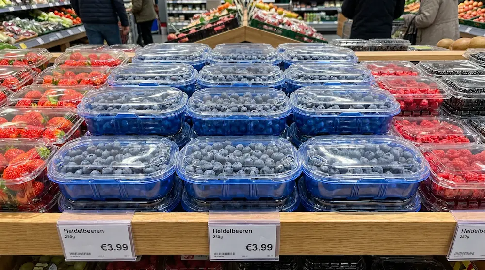 250g blue base clamshell box surrounded by mixed berry packaging in supermarket display