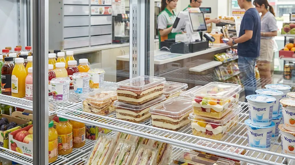 Clear PET/RPET rectangular dessert containers with anti-fog lids in a convenience store refrigerated display beside drinks and yogurt