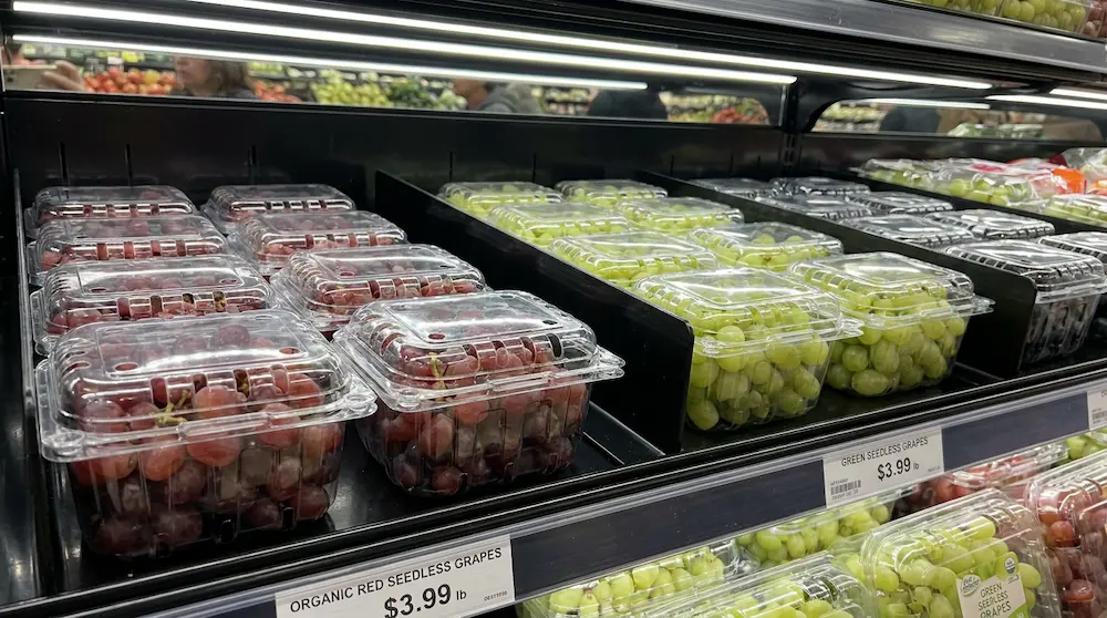 Clear wide vented PET/rPET fruit clamshell containers for grapes in a chilled supermarket shelf
