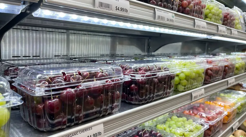 Wide vented PET/rPET fruit clamshell containers for cherries and grapes on refrigerated supermarket shelves