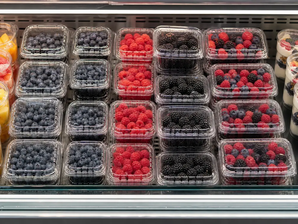 Best Blackberry Clamshell Containers for Retail Display, Takeaway, and Chilled Food 12 Blackberry and mixed berry clamshell containers arranged in a chilled retail display case.