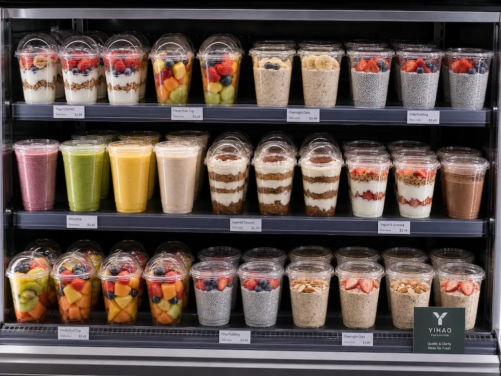 Wholesale Durable Cold Cups: Manufacturer and Supplier Checklist 3 Clear cold cups in a refrigerated display for yogurt parfaits, fruit cups, overnight oats, chia pudding, and smoothies.
