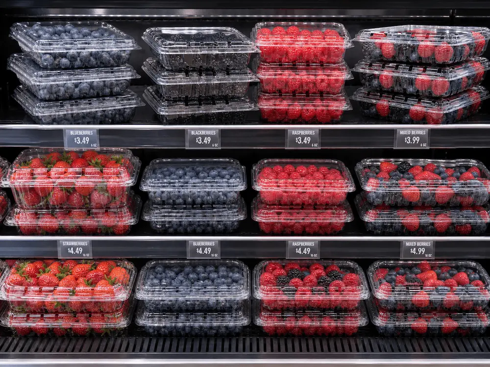 Complete Guide to Berry Clamshell Packaging for Blueberries, Blackberries, and Raspberries 4 Clear PET berry clamshells displaying blueberries, strawberries, raspberries, and blackberries in a supermarket cooler