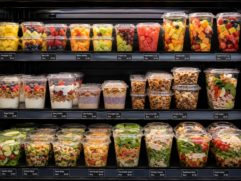 Clear PET Fruit Cups vs Alternative Packaging: How Buyers Should Choose 3 Clear PET fruit cups in refrigerated retail display for fruit salad, parfaits, nuts, and chilled food