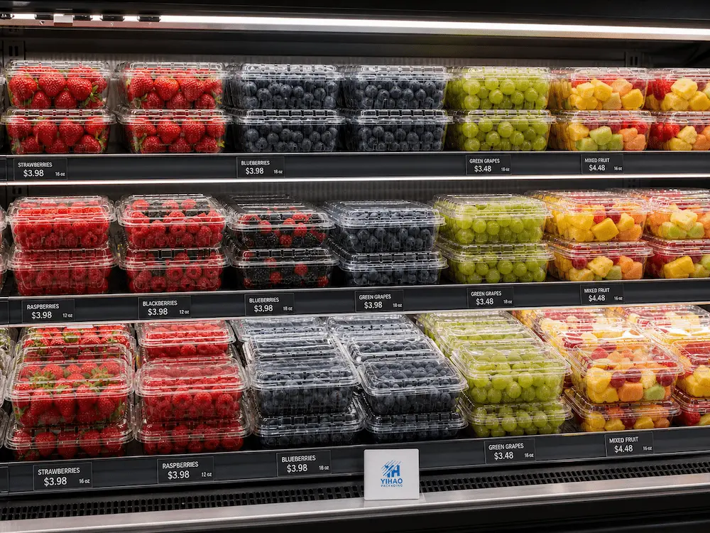 Clear PET Produce Packaging FAQ: Materials, Sizes, Uses, and Ordering Questions 7 Clear PET produce containers in a supermarket cold shelf for strawberries, blueberries, raspberries, grapes, and fresh-cut fruit display
