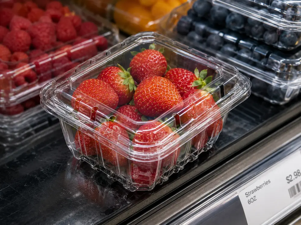 Clear PET strawberry clamshell tray displayed in a supermarket chilled shelf.
