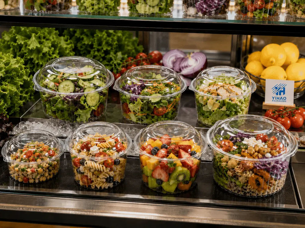 Refrigerated deli display case filled with salads and prepared foods in clear PET containers.