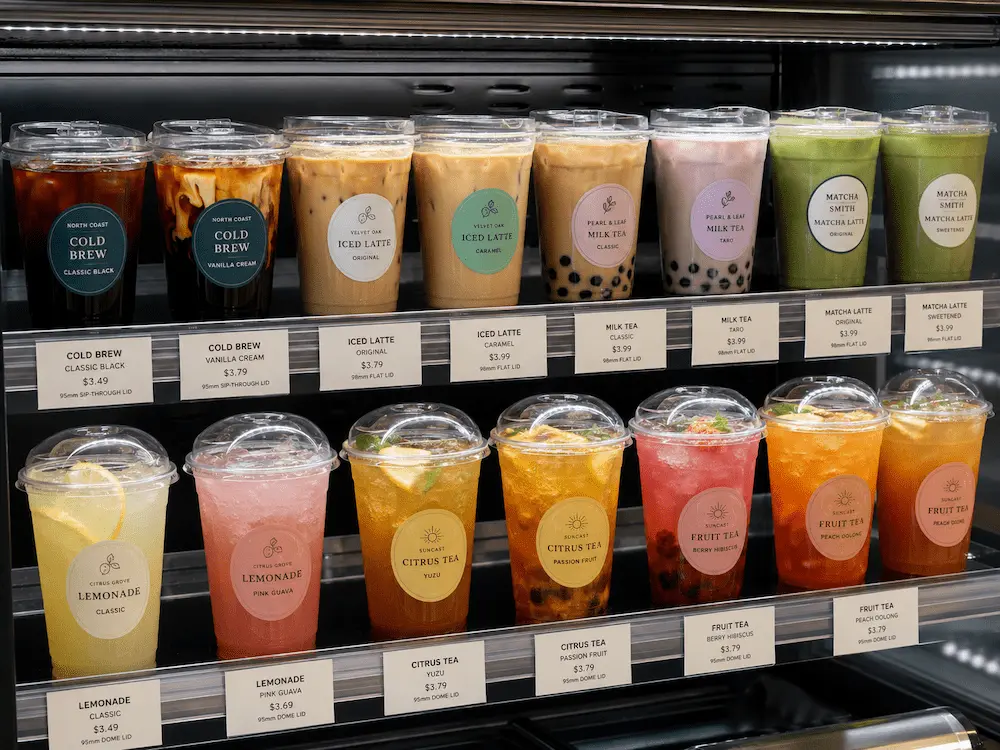 Coffee Cups with Lids FAQ: Materials, Sizes, Uses, and Ordering Questions 3 Refrigerated display of clear coffee cups with lids for cold brew, iced latte, milk tea, matcha, and fruit tea.