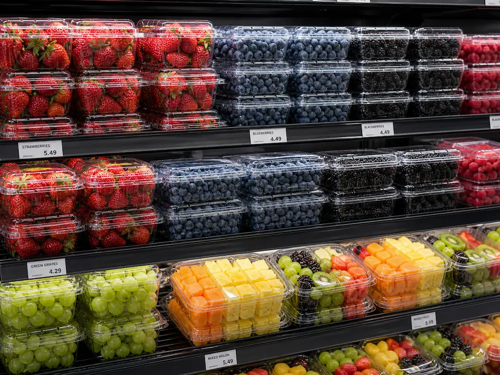 Clear packaging for strawberries, blueberries, blackberries, grapes, and fresh-cut fruit in a supermarket refrigerated display