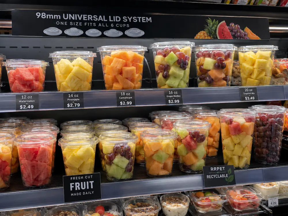 Convenience Store Fruit Cups vs Alternative Packaging: How Buyers Should Choose 1 Clear PET fruit cups in a convenience store display with a 98 mm universal lid system for fresh-cut fruit.