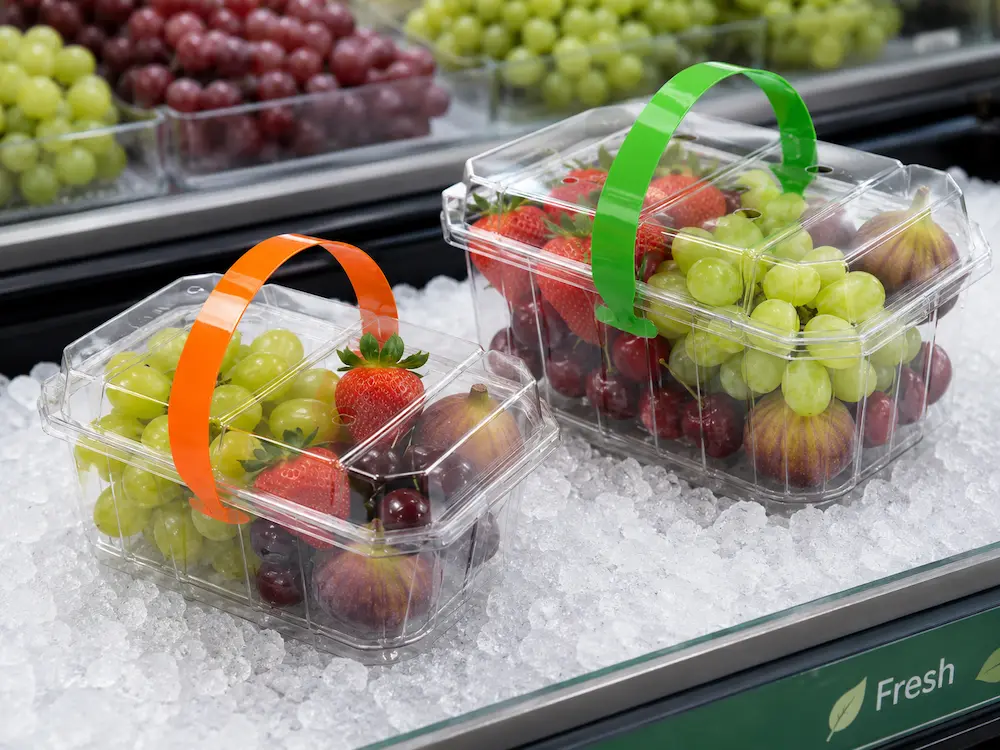 Clear handled fruit containers tested in a chilled display with grapes, strawberries, and figs