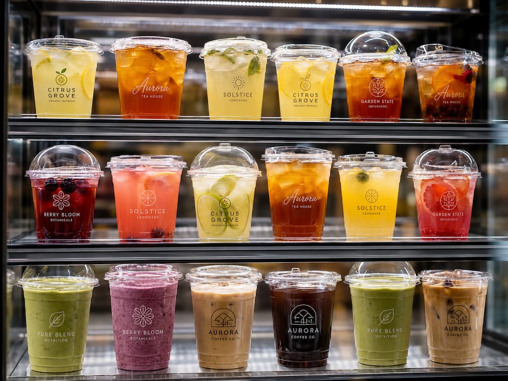 Custom Cup Manufacturer FAQ: Materials, Sizes, Uses, and Ordering Questions 4 Clear cold cups with custom branding displayed in a refrigerated beverage case for retail and grab-and-go drinks