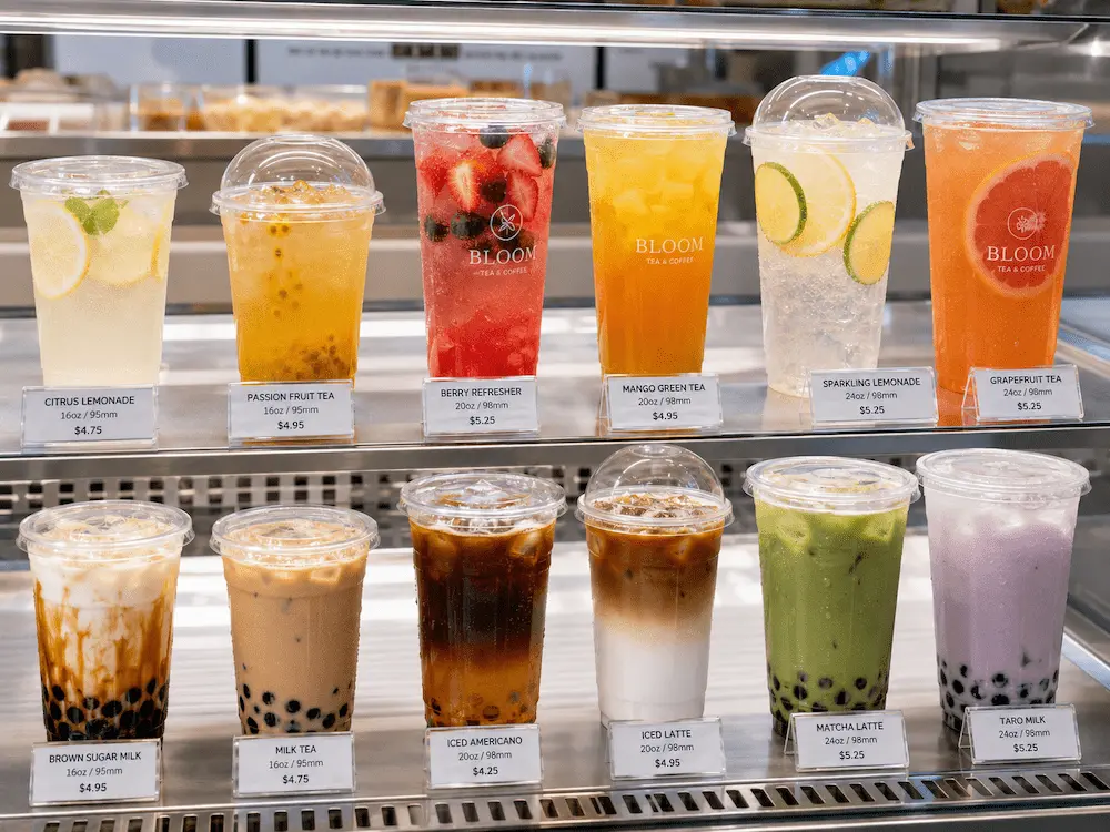 PET Bubble Tea Cups vs Alternative Packaging: How Buyers Should Choose 2 Clear PET bubble tea cups displayed in a refrigerated beverage case with fruit tea, milk tea, matcha, lemonade, and iced coffee