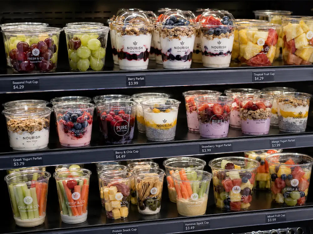 Clear PET cups displaying yogurt parfaits, fresh fruit cups, and snack cups in a refrigerated retail case
