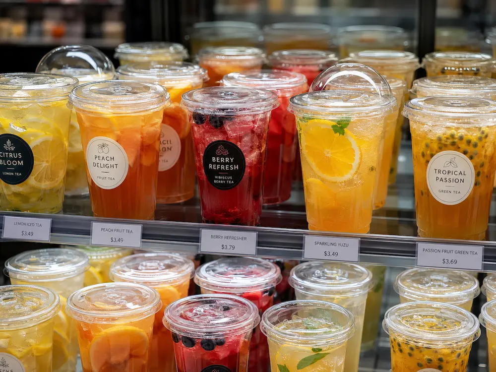 Clear PET drink cups for juice, lemonade, refreshers, and fruit tea in a chilled retail display