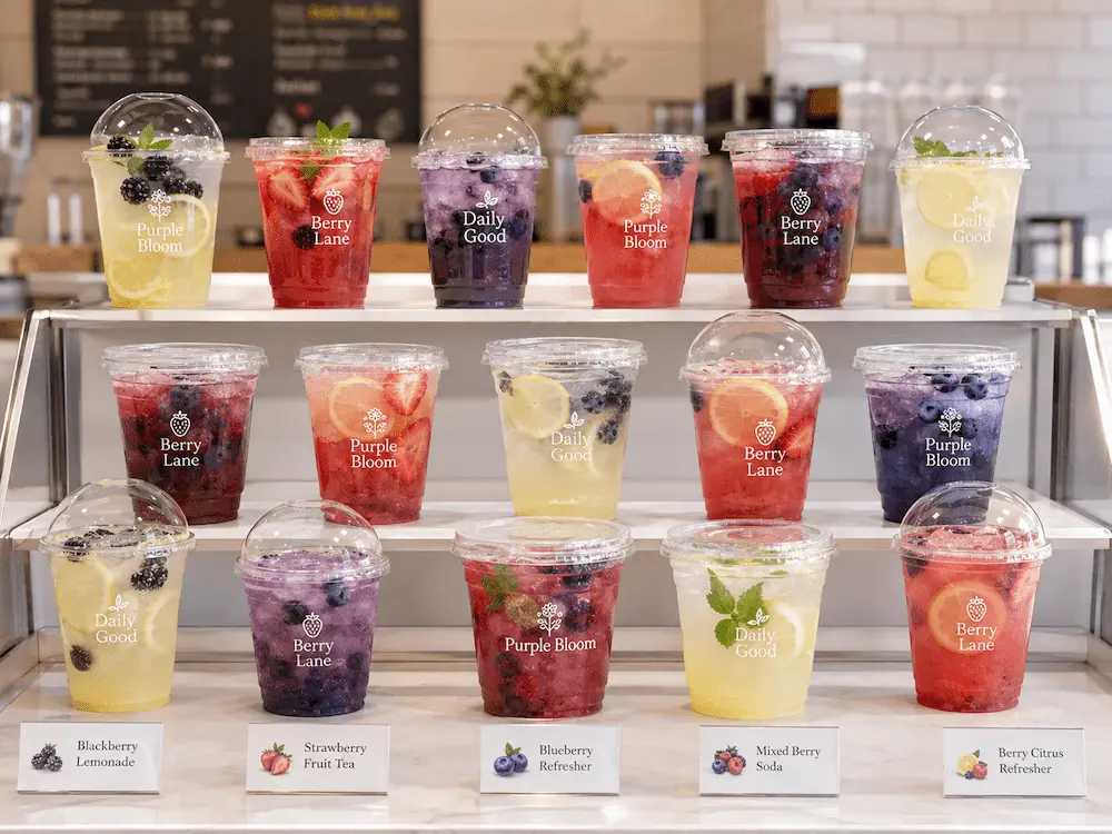 Clear PET and RPET cold cups displaying berry refreshers, lemonade, and fruit drinks on a cafe counter