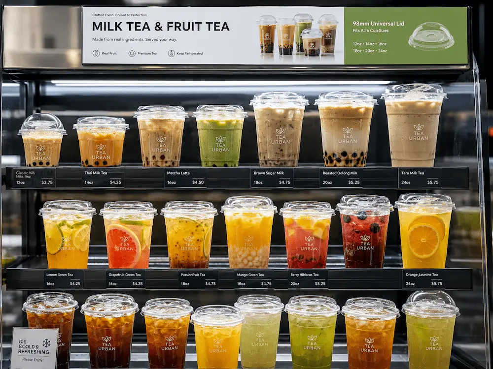 Milk tea cups and fruit tea cups displayed in a refrigerated beverage case with clear PET lids