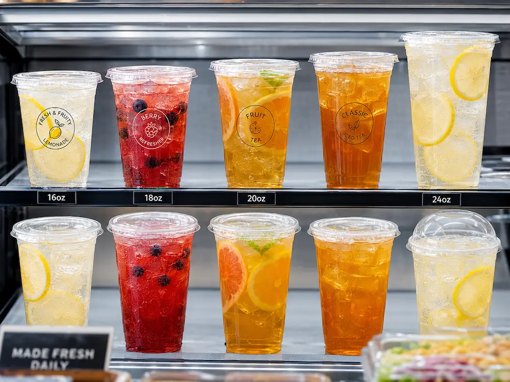 Clear PET cold cups in chilled retail display for sparkling lemonade, berry refreshers, fruit tea, and iced tea