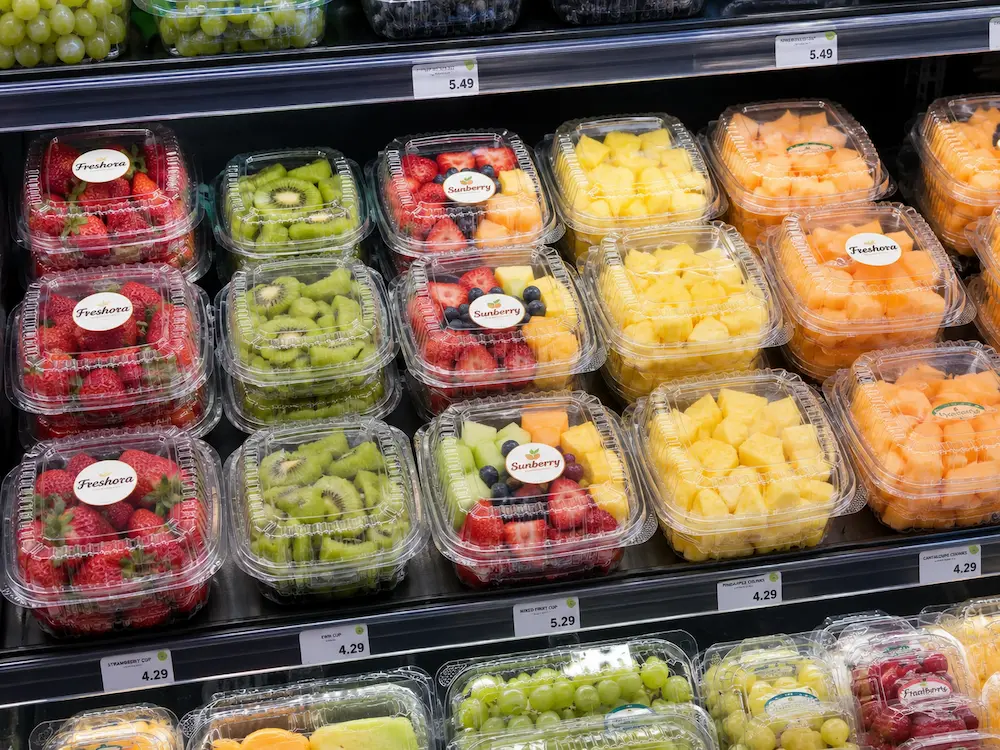 Clear PET fruit clamshell containers displayed in a supermarket refrigerated produce shelf