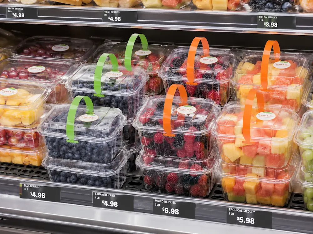 Supermarket chilled display with clear PET fruit containers for berries grapes and mixed fruit packs