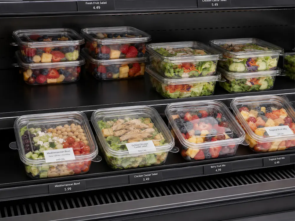 Supermarket cold shelf display with clear salad containers and fruit salad packaging