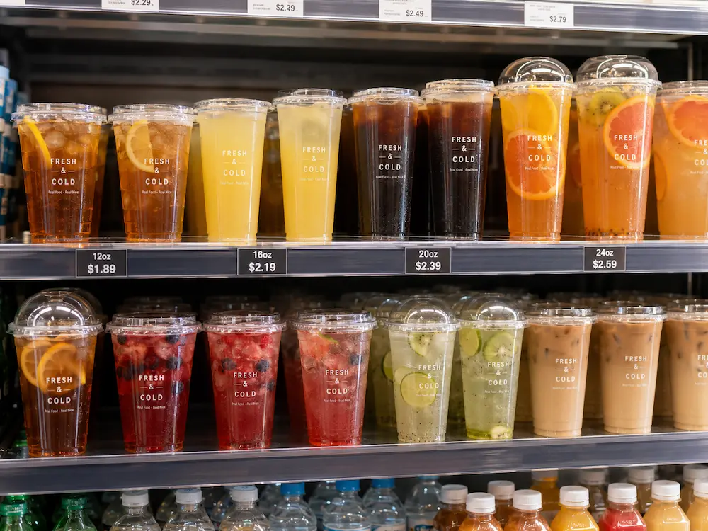 retail shelf display of clear PET cold cups with juices teas and ready-to-drink beverages